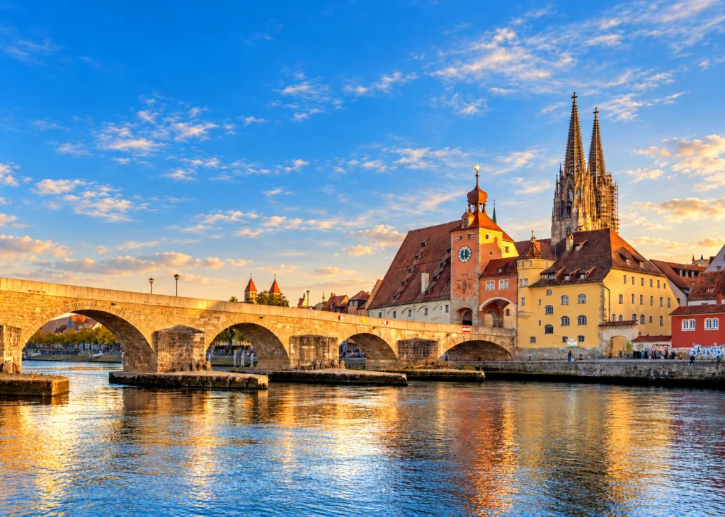 Steinerne Brücke und Altstadtsilhouette von Regensburg mit Brückturm und Dom St. Peter im Sonnenuntergang