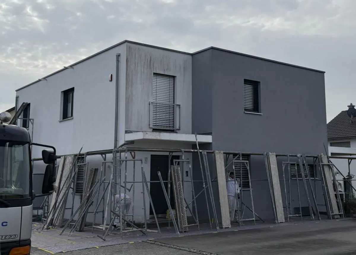 Fassade des Objekts im Raum Ingolstadt vor der Sanierung: Verschmutzungen und Wasserfahnen an der Oberflaeche, Gerüst im Aufbau