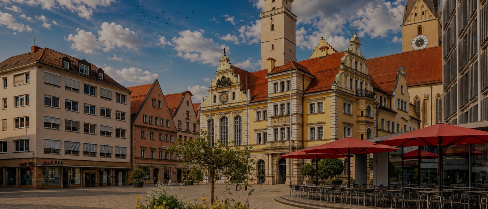Rathausplatz in Ingolstadt mit dem Alten Rathaus, dem Pfeifturm und der Pfarrkirche Sankt Moritz an einem sonnigen Sommertag