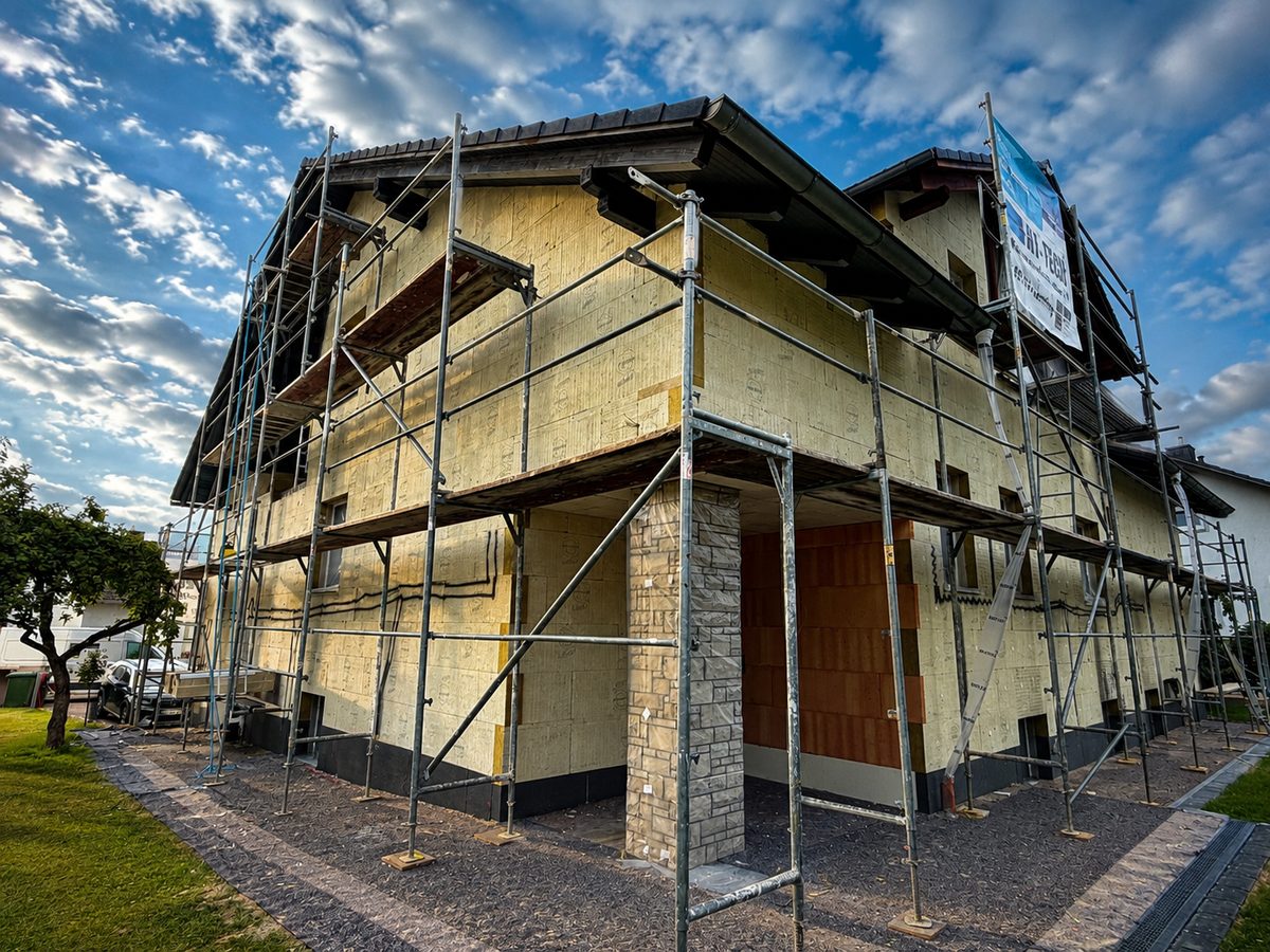 Eingerüstetes Wohnhaus mit montierten Mineralwolle-Dämmplatten vor dem Aufbringen der Armierungsschicht, Fensteröffnungen provisorisch verschlossen, Sockelbereich bereits abgesetzt